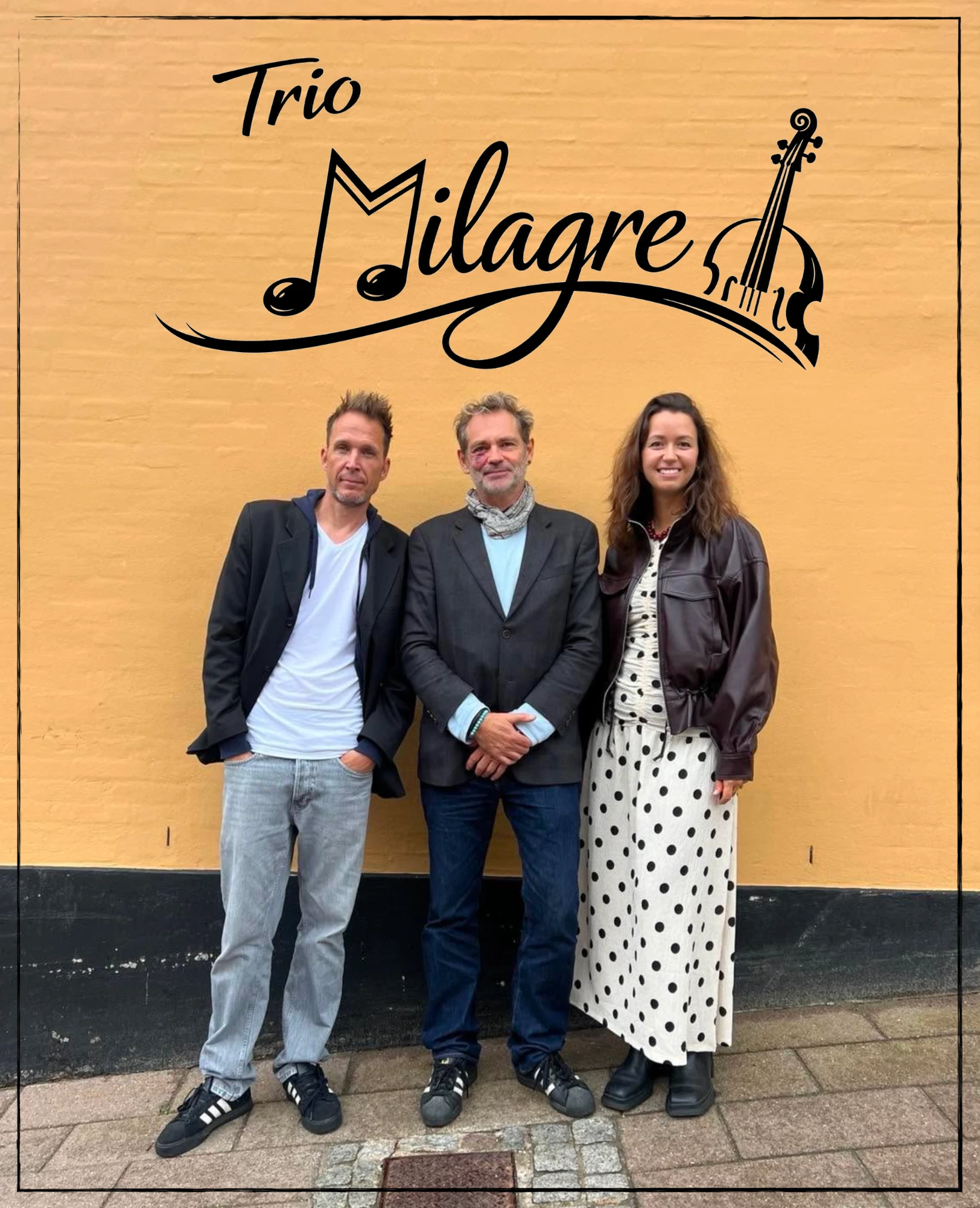 Trio Milagre foran en gul mur